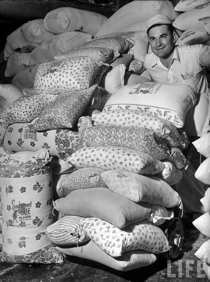 A man standing with colorful patterned flour sacks ready for the store